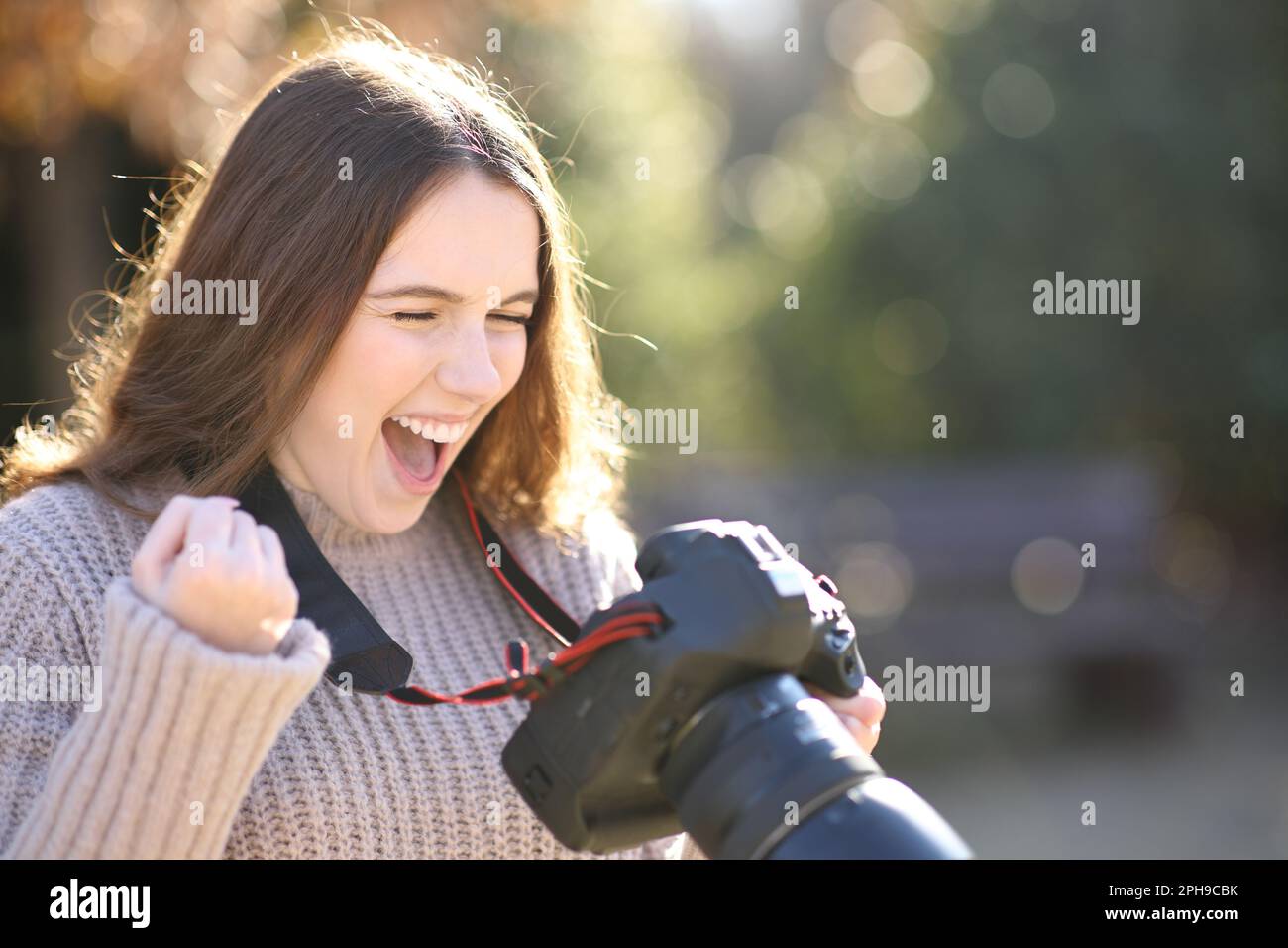Aufgeregter Fotograf, der Fotos überprüft, um den Erfolg im Winter mit der Kamera zu feiern Stockfoto