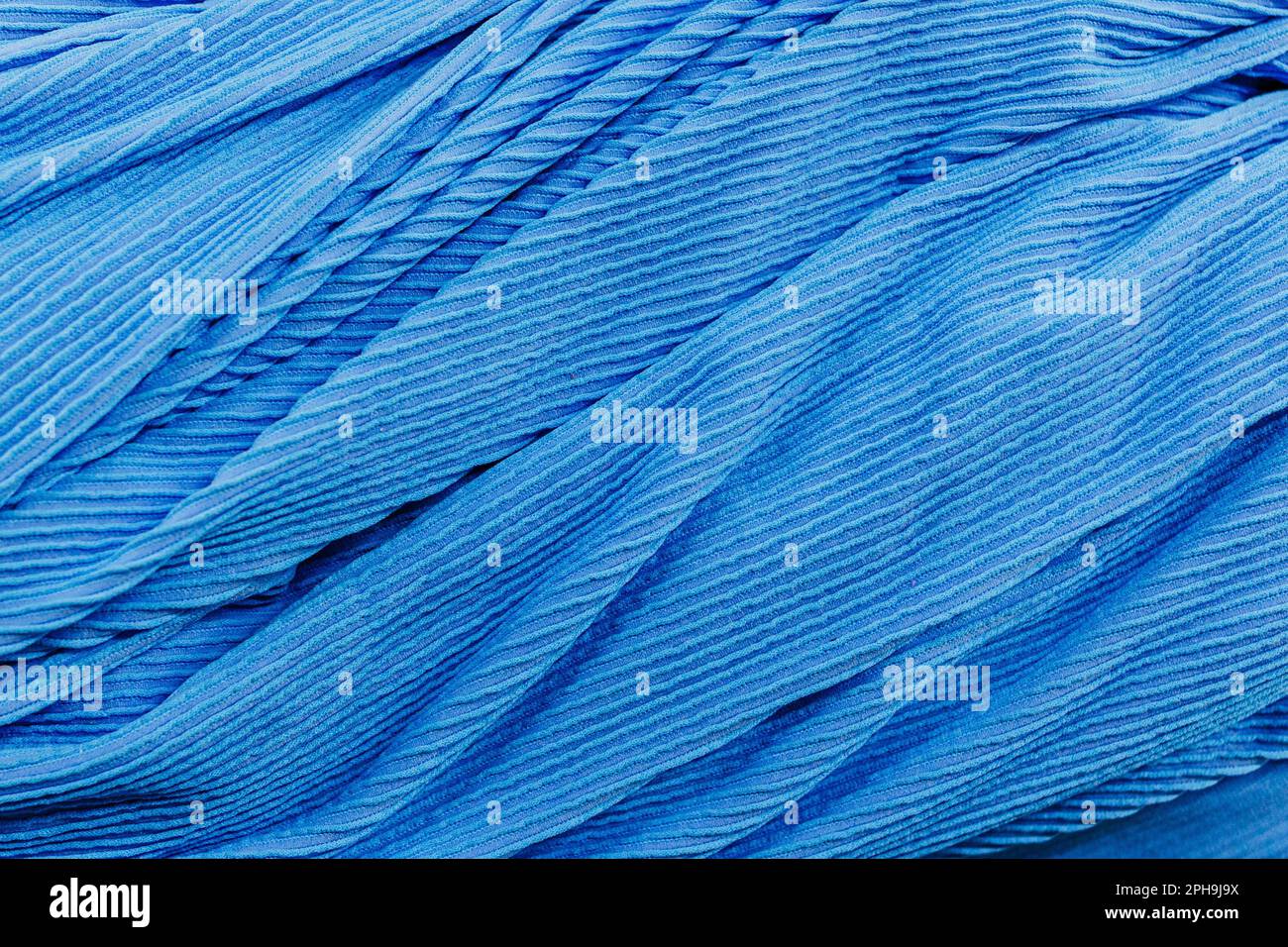 Nahaufnahme eines strukturierten blauen Stoffes mit einer Reihe komplizierter Wellenfalten Stockfoto