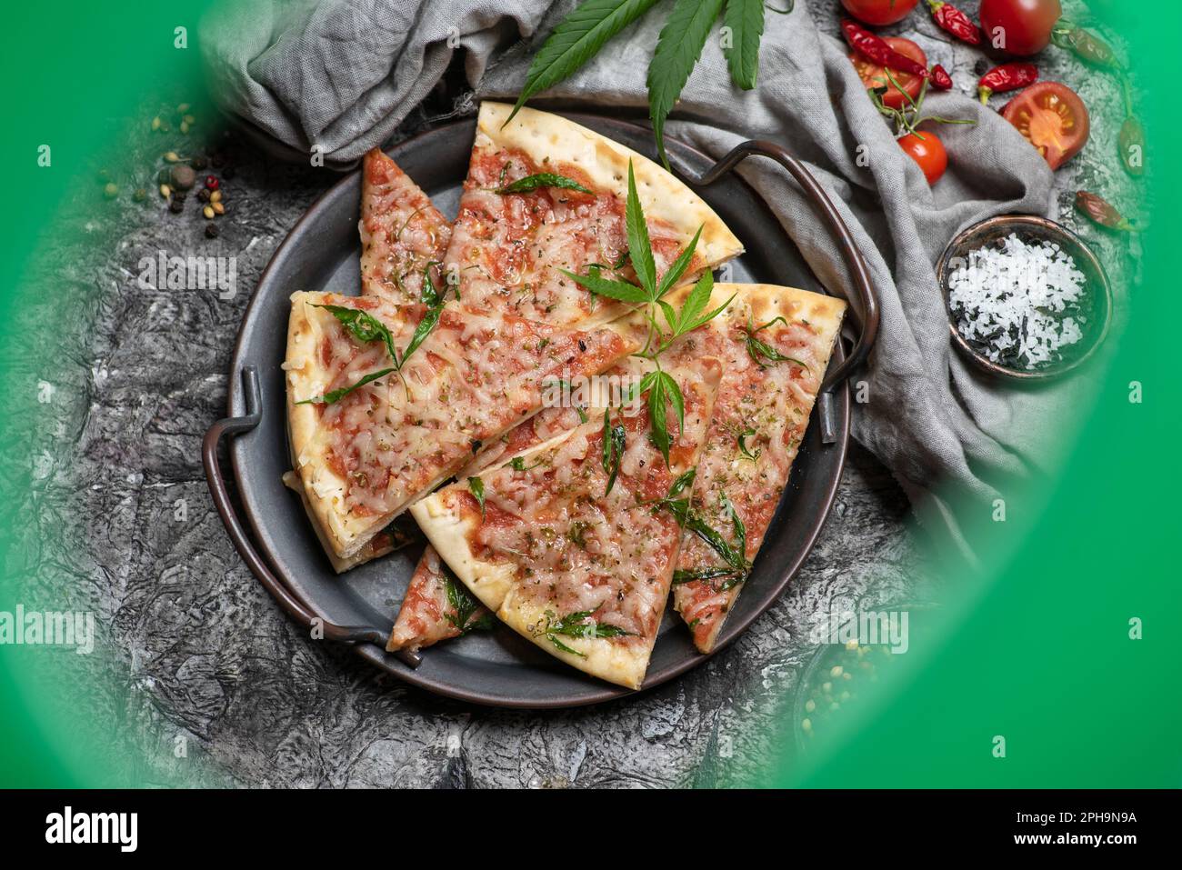 Pizzaschneiden mit Marihuana-Blättern in einer Metallschüssel auf dunklem Holzhintergrund Stockfoto