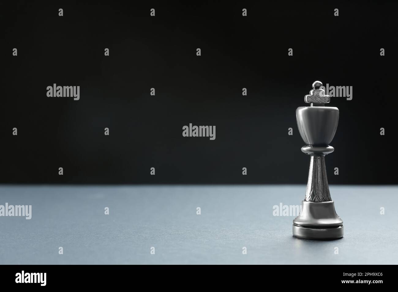 Metallkönig auf dem Tisch vor dunklem Hintergrund, Platz für Text. Schachfigur Stockfoto