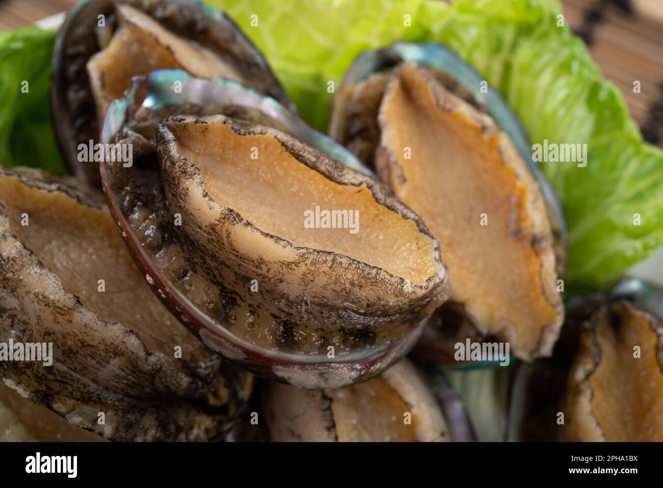 Köstliche rohe Abalone auf einem Teller mit Salat auf Holztisch. Stockfoto