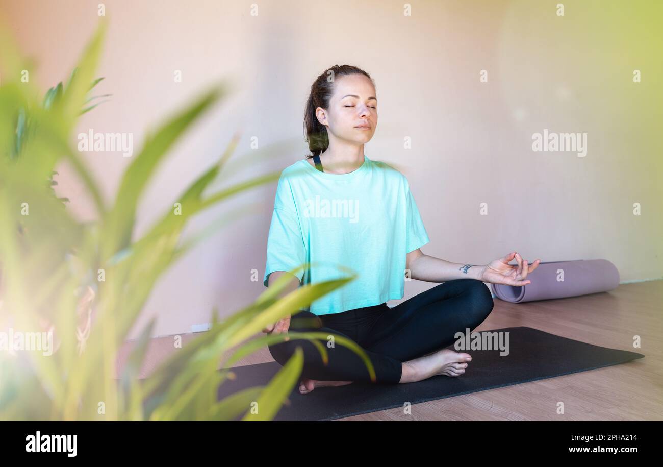 Brünette Frau, die in Lotusstellung meditiert. Stockfoto