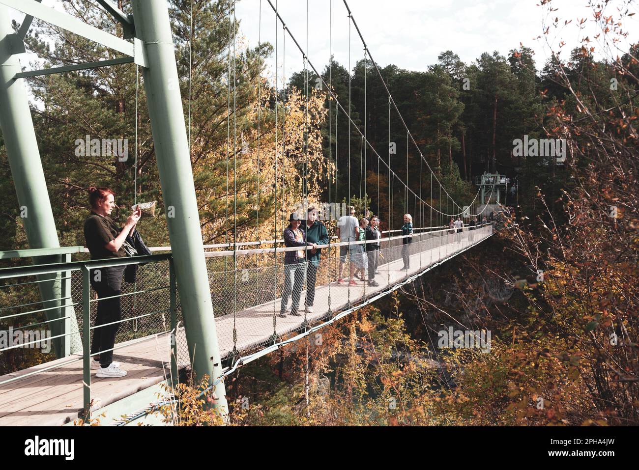 Viele Touristen gehen entlang der Hängebrücke über den Fluss Katun zur Insel in den Bergen im Wald, um die Sehenswürdigkeiten in Altai zu beobachten Stockfoto