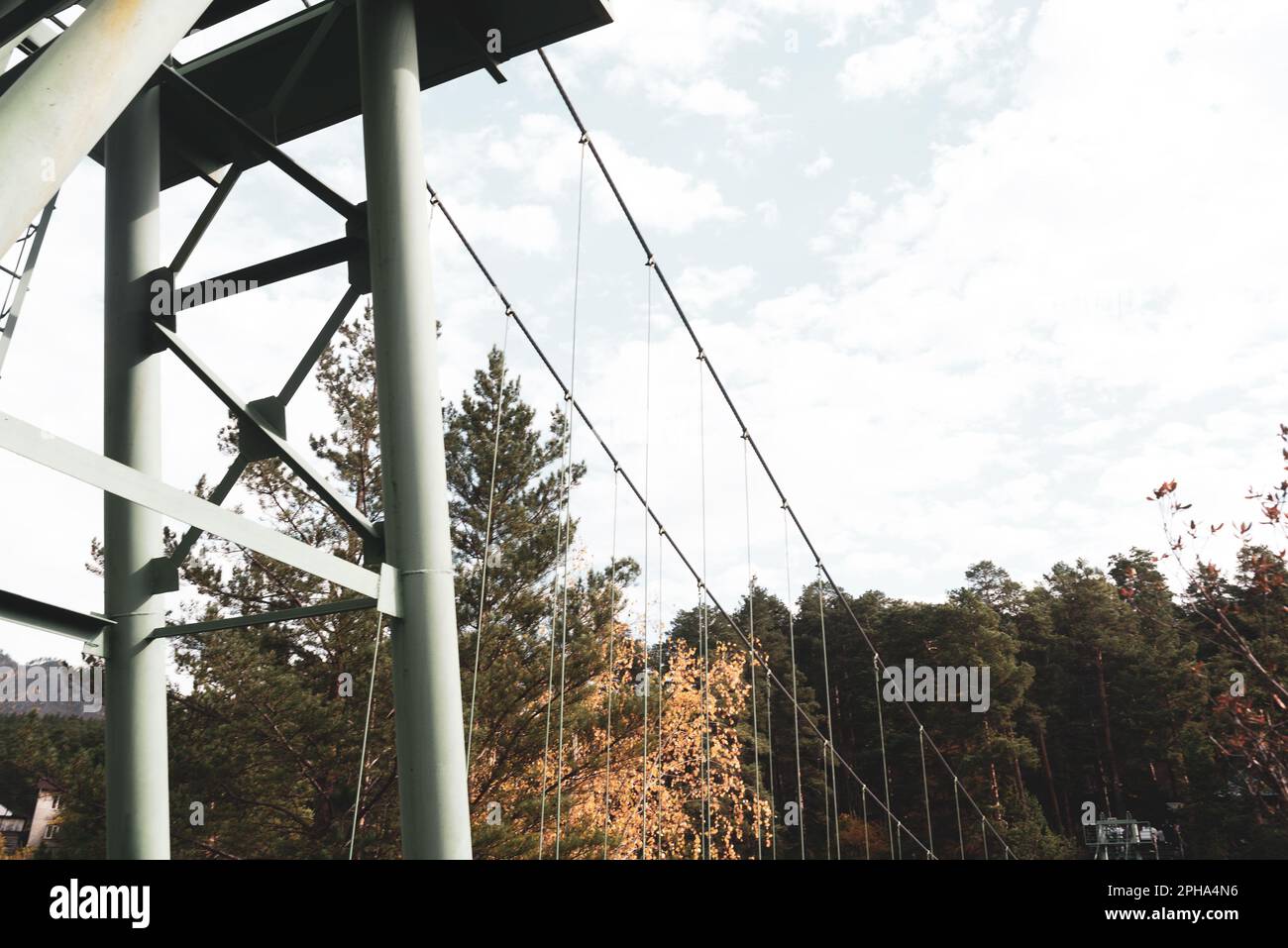 Metallstützen einer Hängebrücke mit Kabeln vor dem Hintergrund von Waldbäumen in Altai. Stockfoto