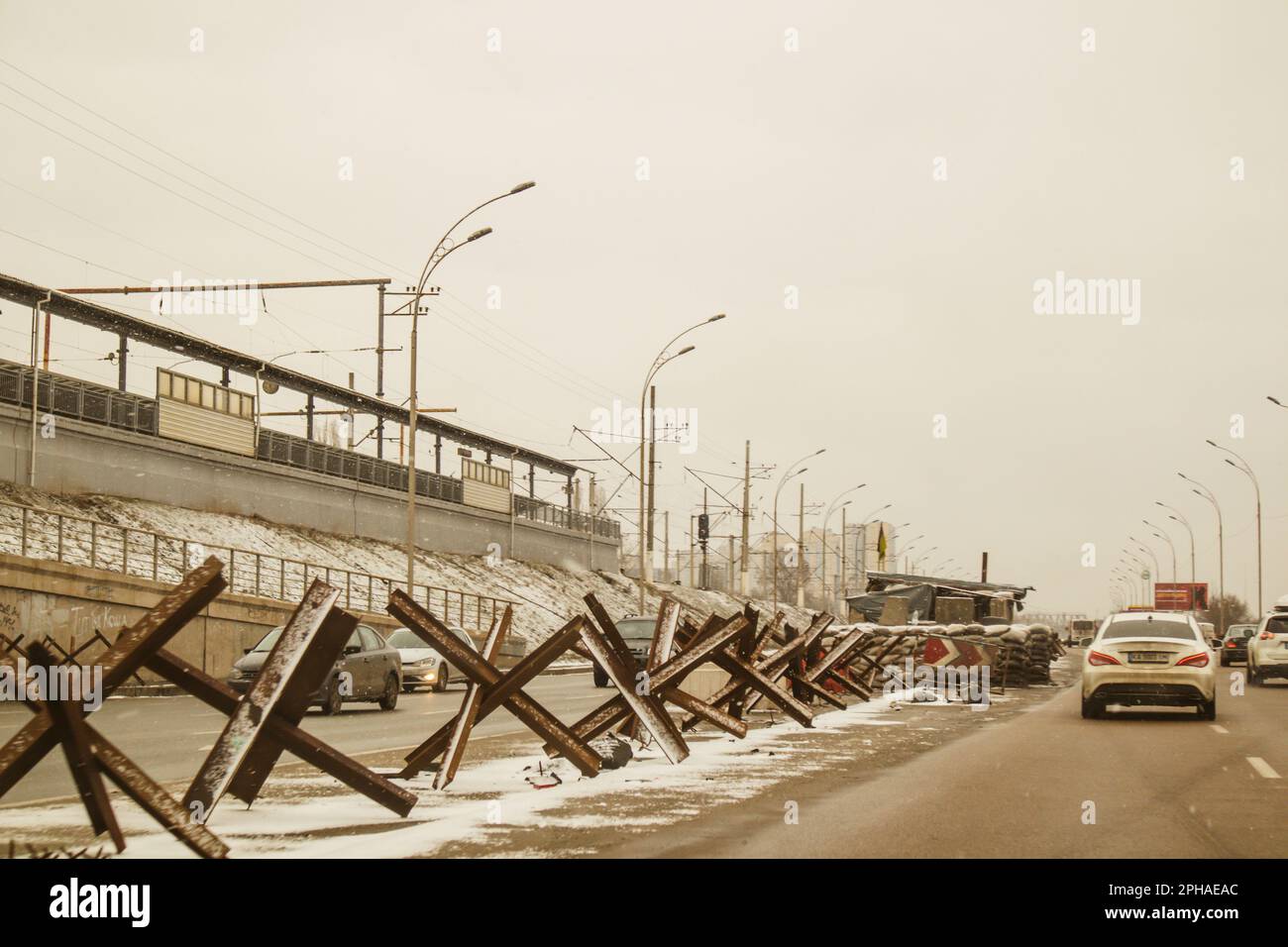 Kiew, Ukraine 2. Februar 2023 Eine Autobahn in einer Militärstadt mit Panzerabwehrbarrieren Igel am Straßenrand. Autos fahren im Winter auf einer Autobahn Stockfoto