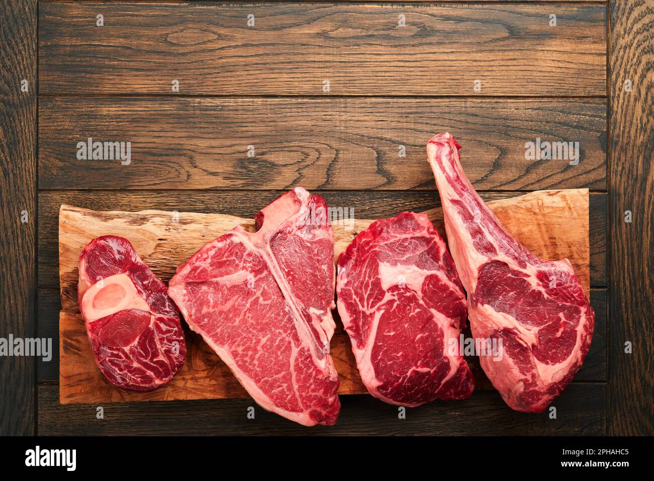 Rohe Prime Steaks. Auswahl an frischen schwarzen angus Prime Steaks T-Bone, New York, Ribeye, Striploin, Tomahawk Schneidebrett auf schwarzem oder dunklem Hintergrund Stockfoto