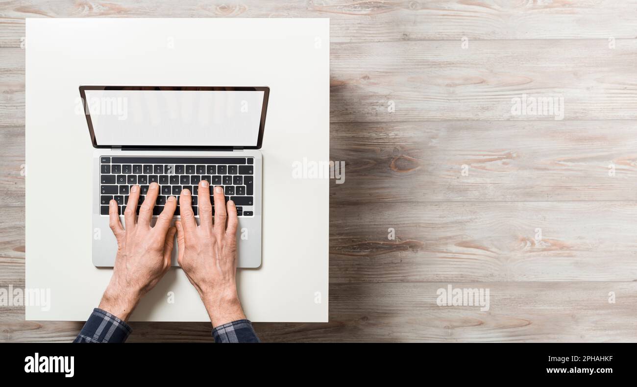 Hände eines Mannes über Laptop mit leerem Bildschirm. Draufsicht mit leerem Kopierbereich. Stockfoto