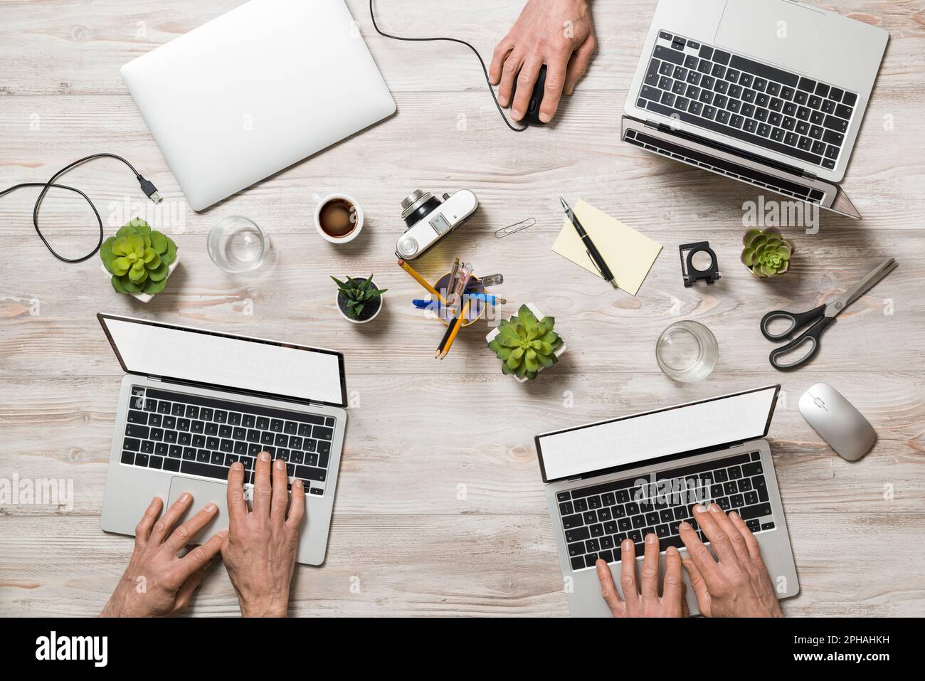 Großer Blickwinkel auf den Bürotisch mit Personen, die am Laptop arbeiten. Stockfoto
