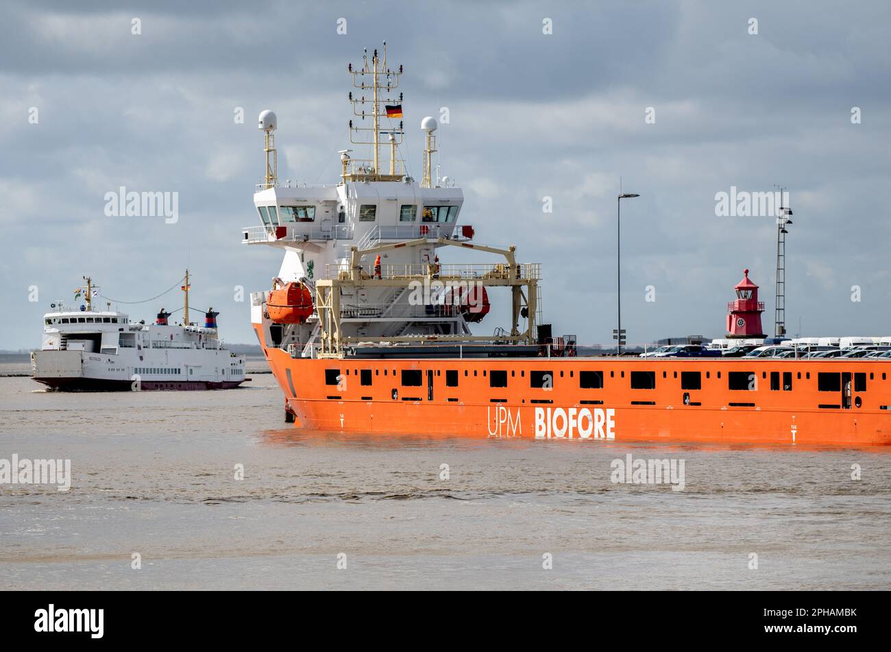 Emden, Deutschland. 27. März 2023. Ein Frachtschiff von UPM Biofore liegt an einer Kaimauer im Außenhafen, während die Inselfähre „Westfalen“ der Schifffahrtsgesellschaft AG-Ems in den Hafen einläuft. Das niedersächsische Wirtschaftsministerium, die niedersächsische Hafenbehörde und die Unternehmen Seaports of Niedersachsen, Niedersachsen Ports und JadeWeserPort Realisierungs GmbH & Co KG berichtete auf einer Pressekonferenz über die aktuelle Lage der niedersächsischen Seehäfen. Kredit: Hauke-Christian Dittrich/dpa/Alamy Live News Stockfoto