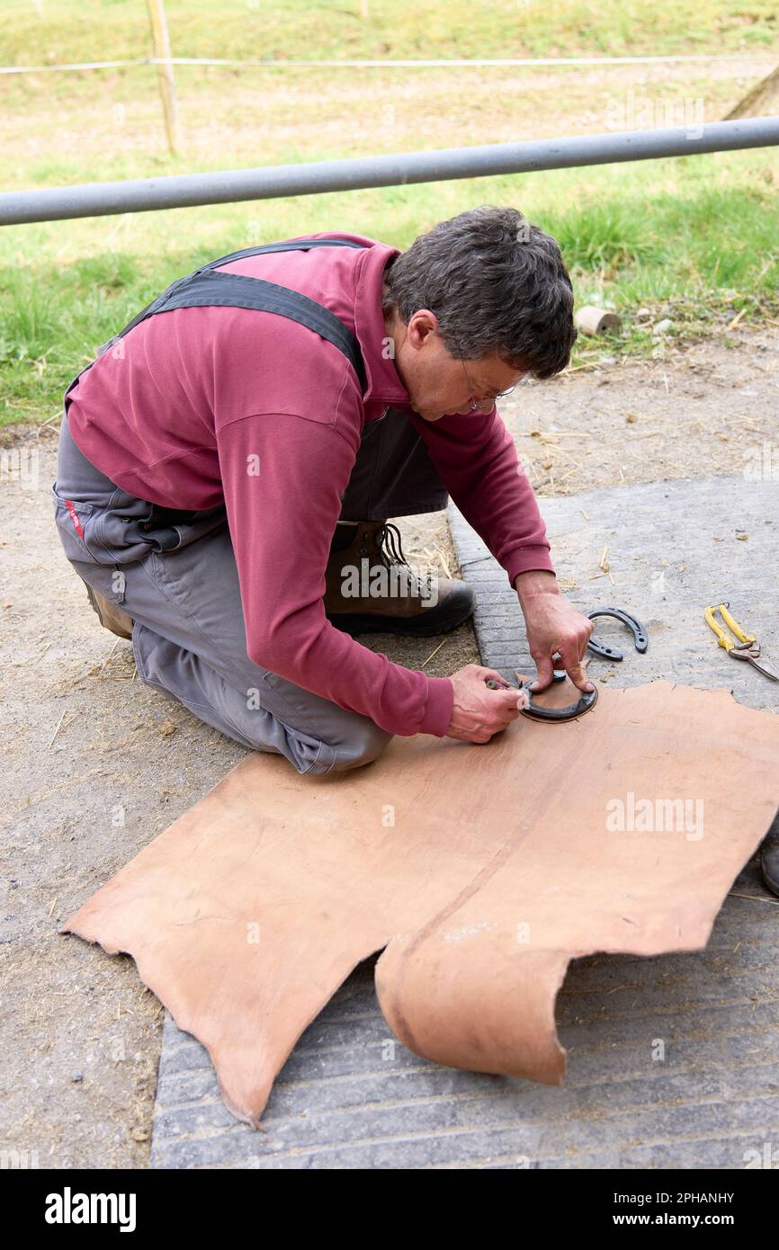 Ein Mann, der die Form eines Hufeisens auf einem Stück Holz umrissen hat, als Vorbereitung für das Schuhlaufen Stockfoto