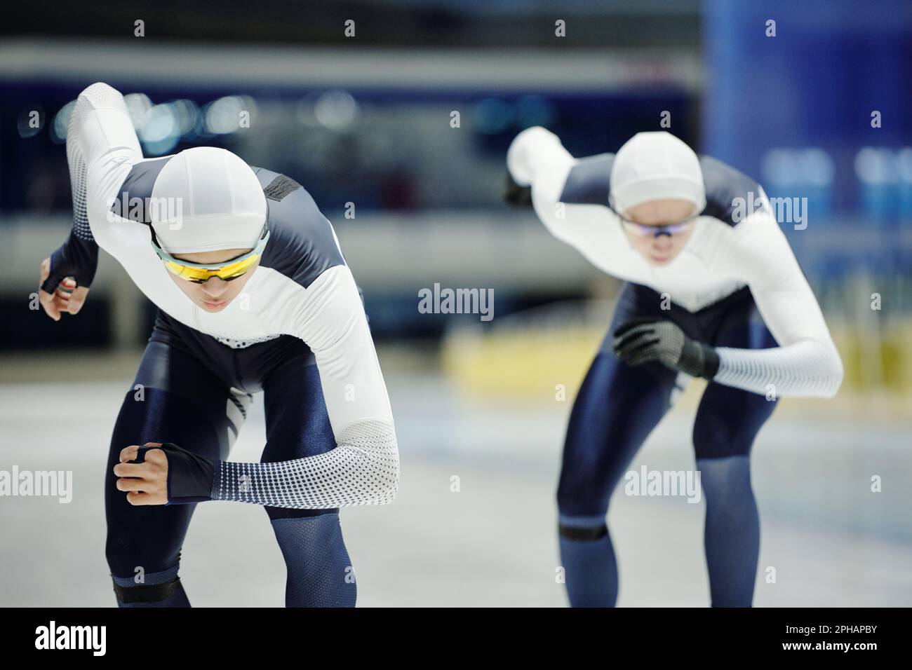 Zwei junge männliche Eiskunstläufer in Sportuniform, die sich auf der Eislaufbahn vorwärts bewegen, während sie an einem Kurzstreckenlauf-Turnier teilnehmen Stockfoto