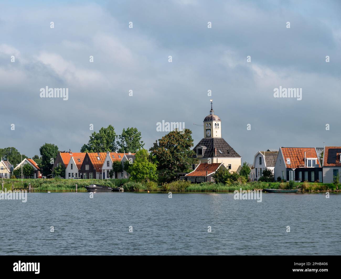 Kirche und Häuser am Deich des Dorfes Durgerdam vom Fluss Buiten IJ in der Nähe von Amsterdam, Niederlande Stockfoto