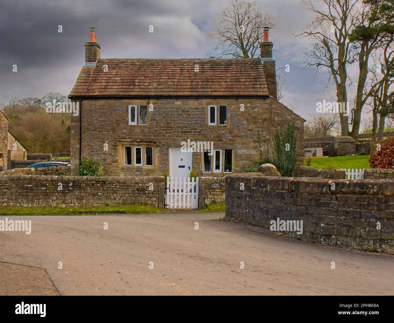 Old Stone Cottage mit Steinfenstern, Steinmauer Garten und zwei weißen Wicket Tore Downham Village, Lancashire, - Historic County Palatine, Stockfoto