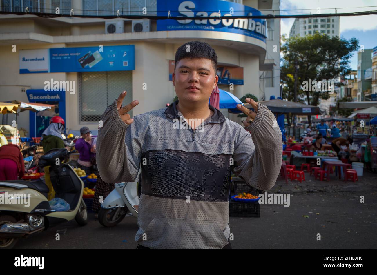 Ein junger vietnamesischer Mann posiert für ein Foto vor dem zentralen Markt in Pleiku im zentralen Hochland Vietnams. Stockfoto