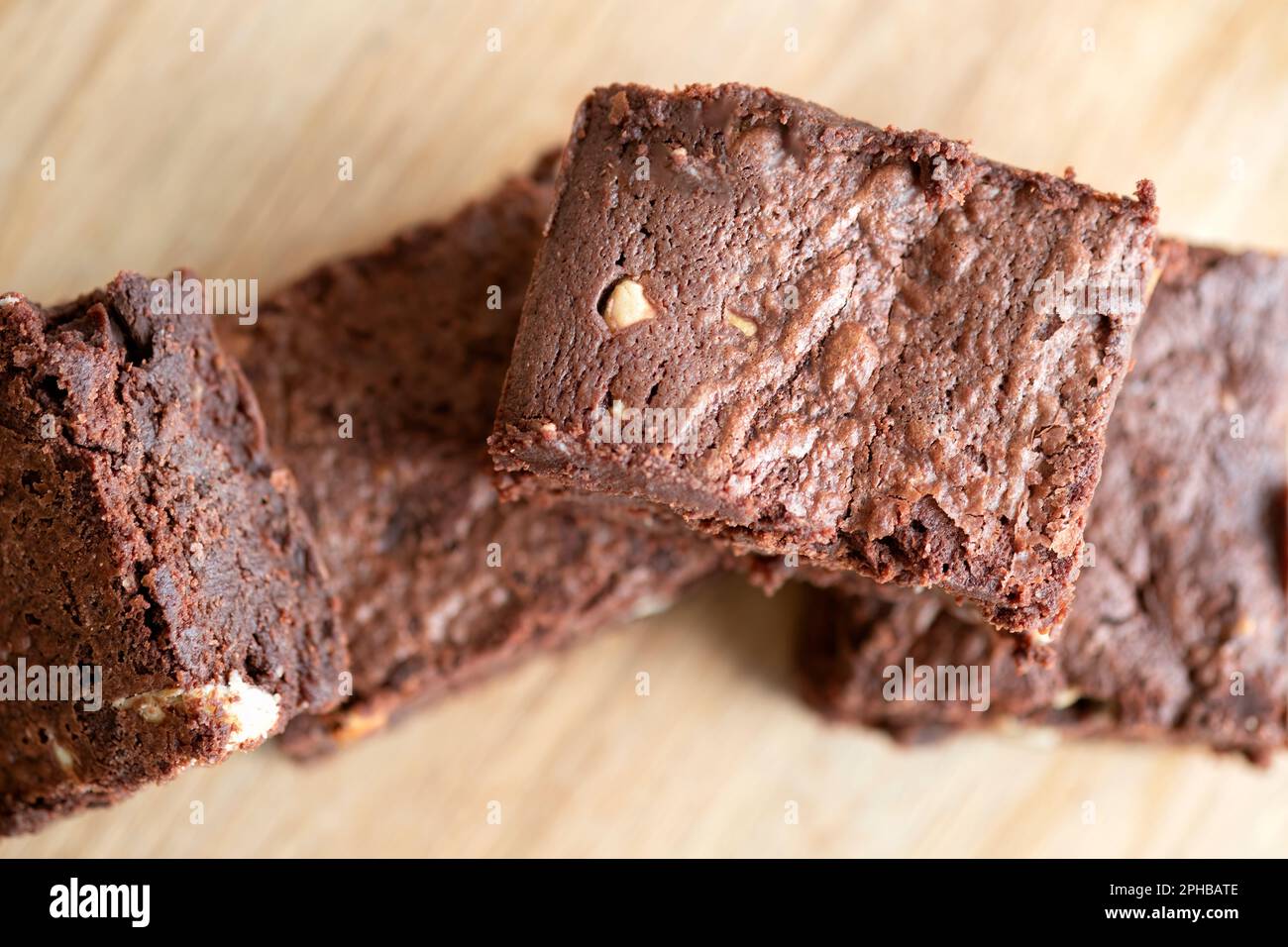 Eine Charge frisch gebackener dreifach-Schokoladen-Brownies auf einer Holzplatte. Die Brownies sind noch warm und klebrig. Ein Genuss Stockfoto