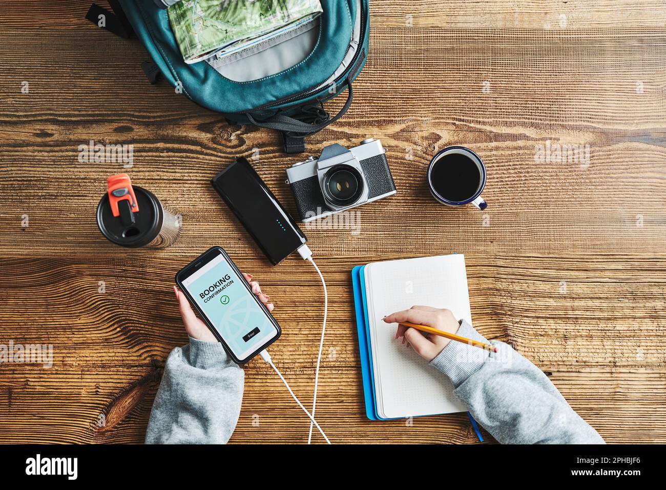Frau, die den nächsten Urlaub plant. Hotelbuchung online über Smartphone. Service wird bestellt. Aufladen des Mobiltelefons mit der Powerbank. Mit Technologie W. Stockfoto
