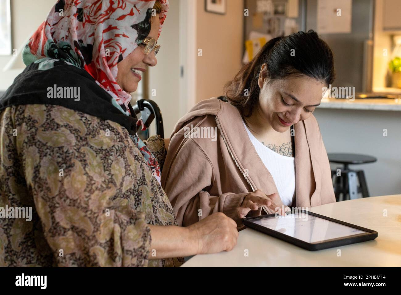 Behinderte Frau, die einen Tablet-PC von der Mutter zu Hause benutzt Stockfoto