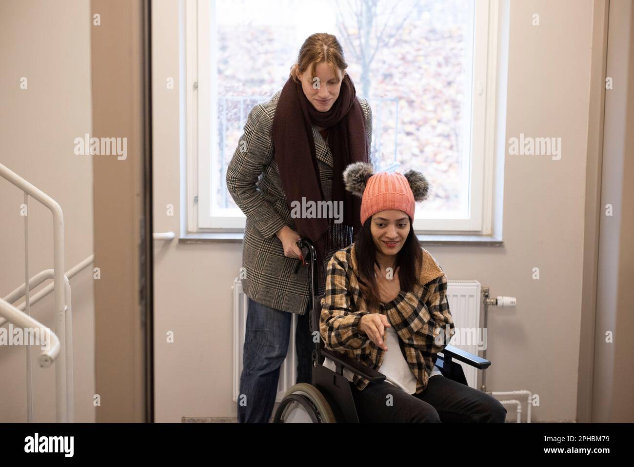 Pflegerin, die zu Hause im Rollstuhl sitzt Stockfoto