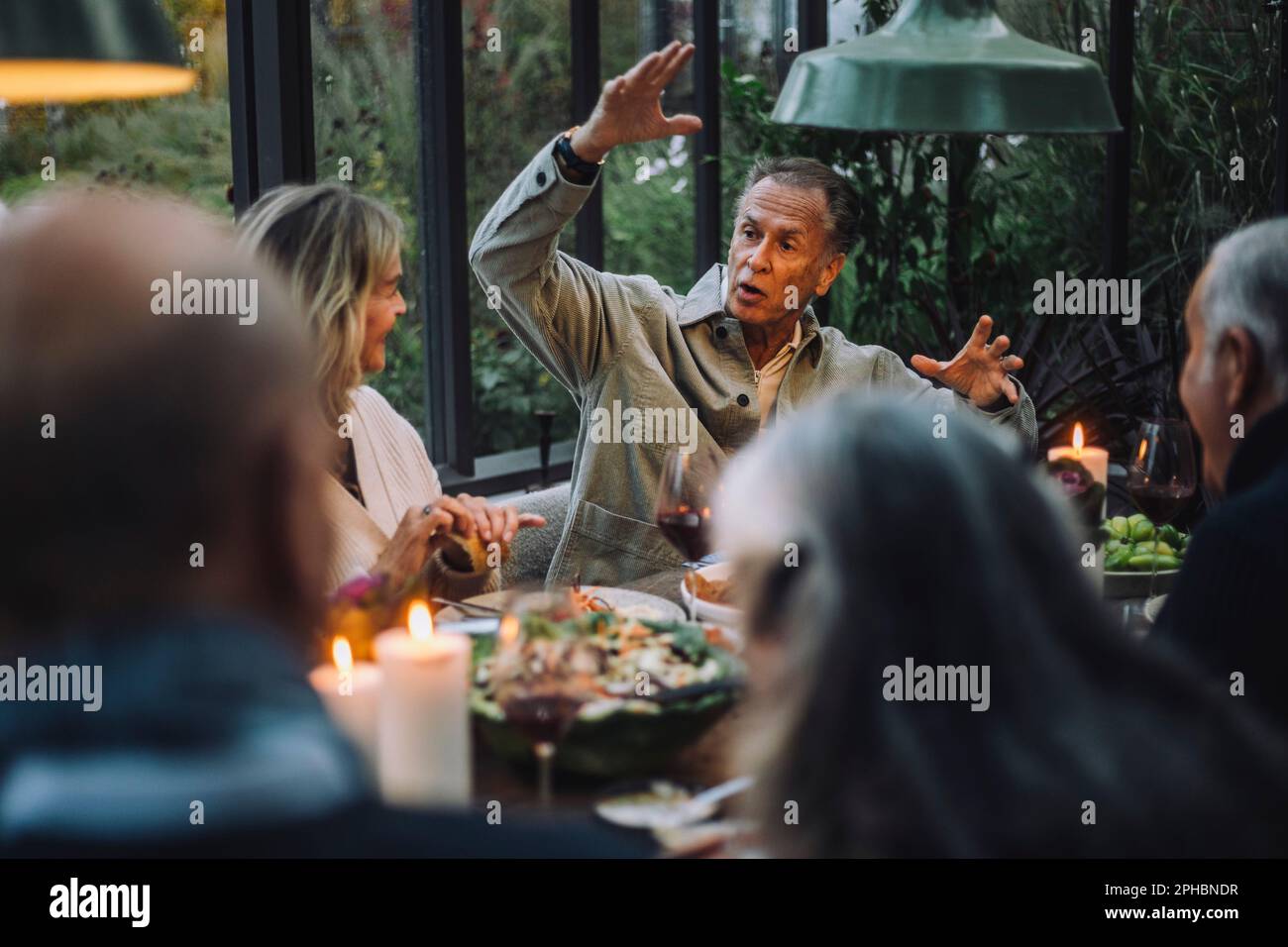 Senioren-Gesten während des Gesprächs mit Freunden während der Dinnerparty Stockfoto