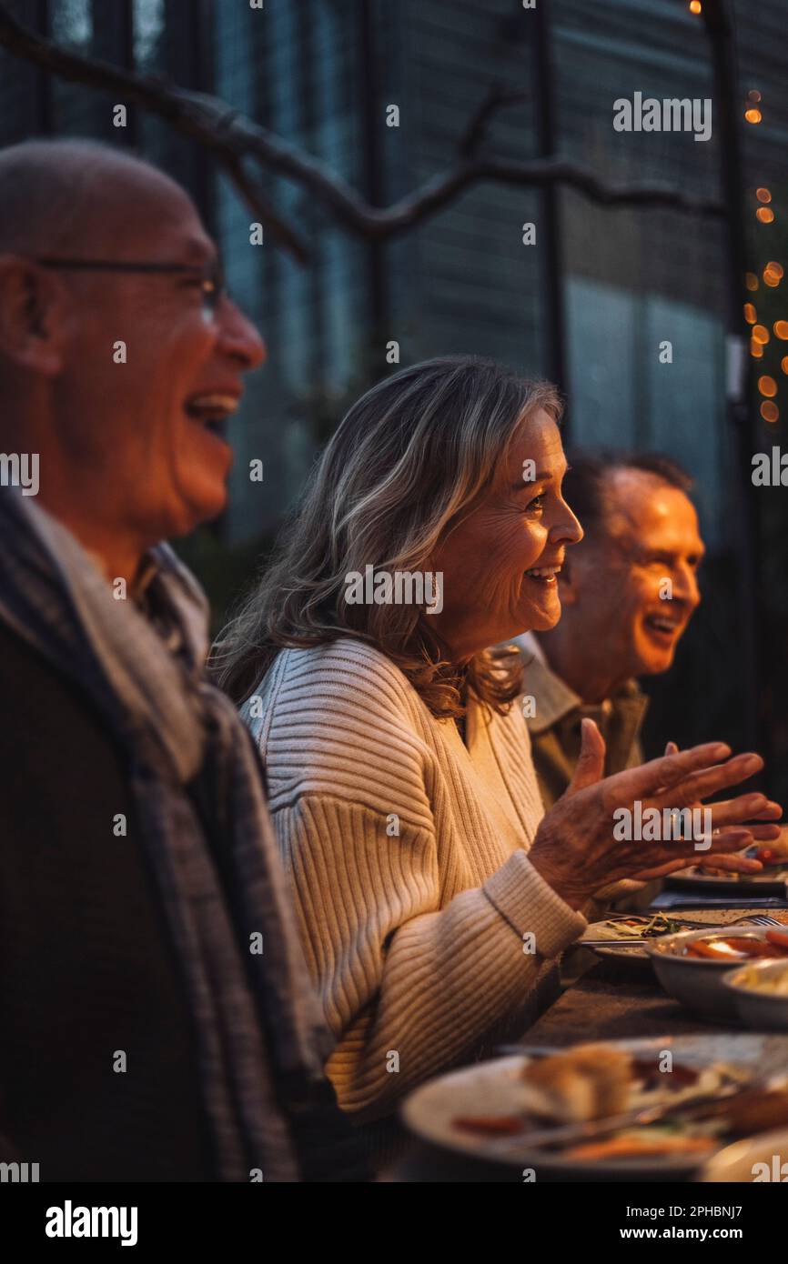 Eine glückliche Seniorin, die auf der Dinnerparty gestikuliert hat Stockfoto