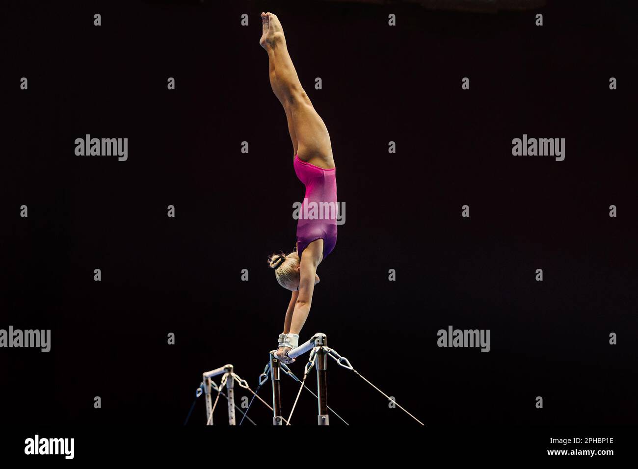 Turnerinnen, die auf unebenen Balken auf schwarzem Hintergrund trainieren, olympische Sportarten sind in den Sommerspielen enthalten Stockfoto