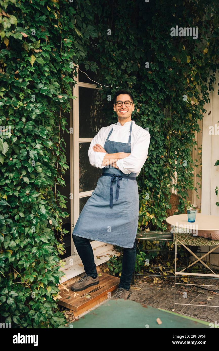 Ein glücklicher Koch, der vor dem Restaurant mit gekreuzten Armen stand Stockfoto