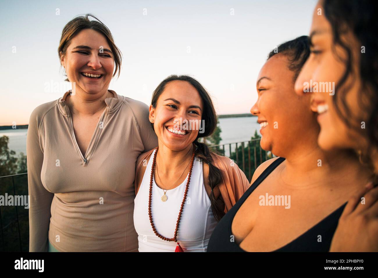Multirassische glückliche weibliche Freunde, die während des Sonnenuntergangs zusammen lachen Stockfoto