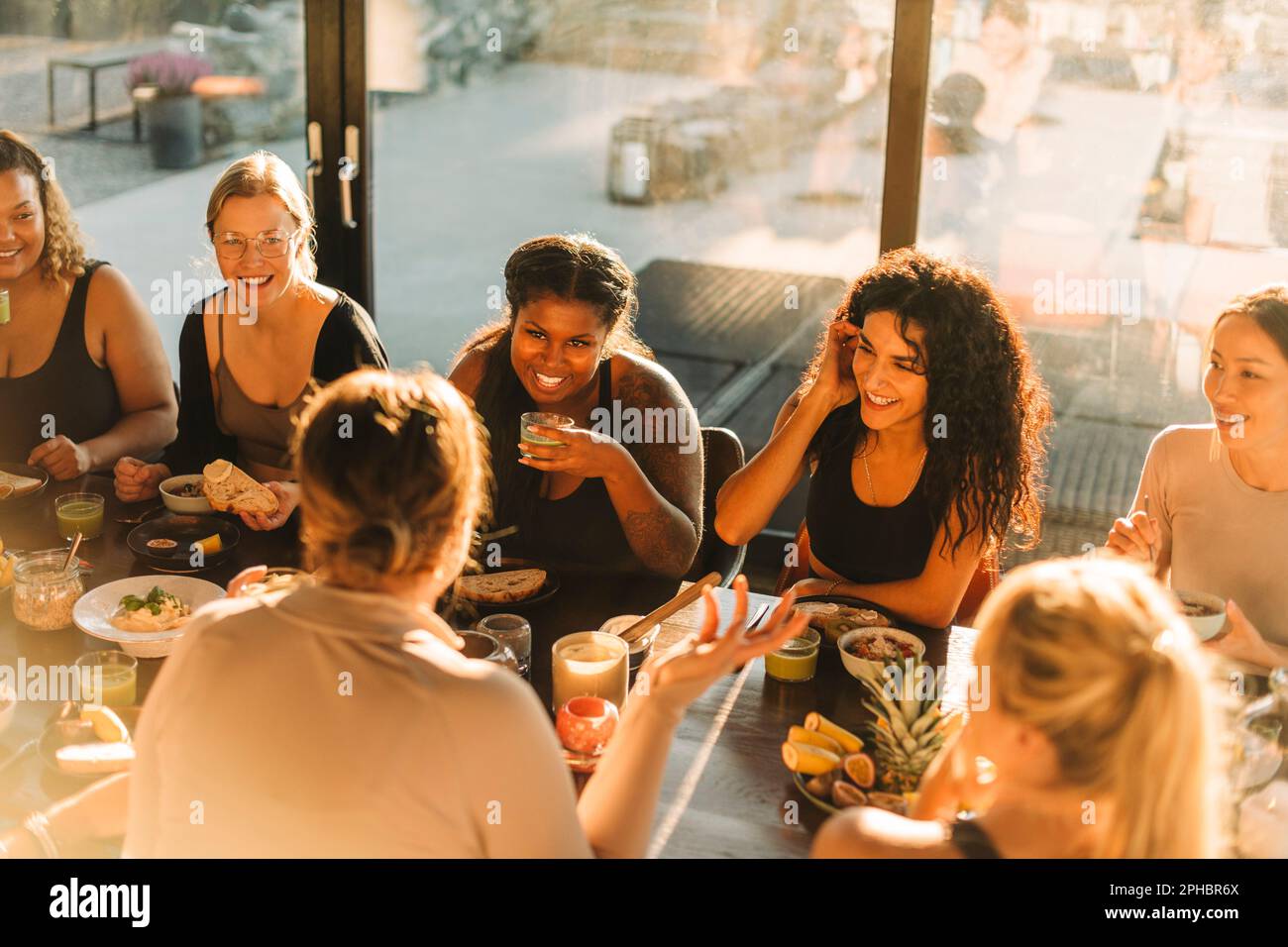 Multirassische weibliche Freunde, die sich unterhalten, während sie im Residenz-Center frühstücken Stockfoto