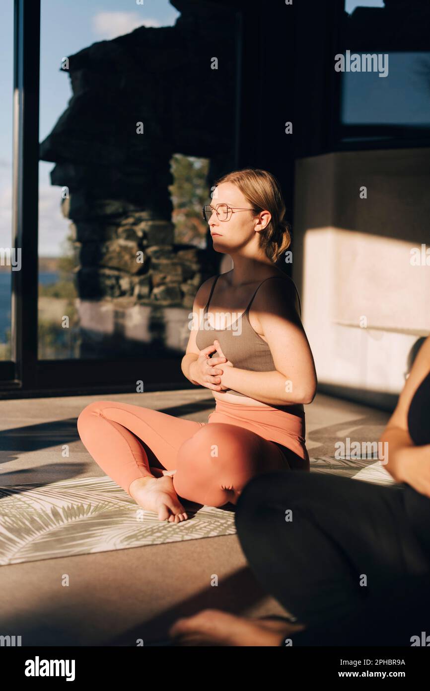 Eine Frau mit den Händen am Magen, die Atemübungen übt und im Rückzugszentrum mit Kreuzbein sitzt Stockfoto