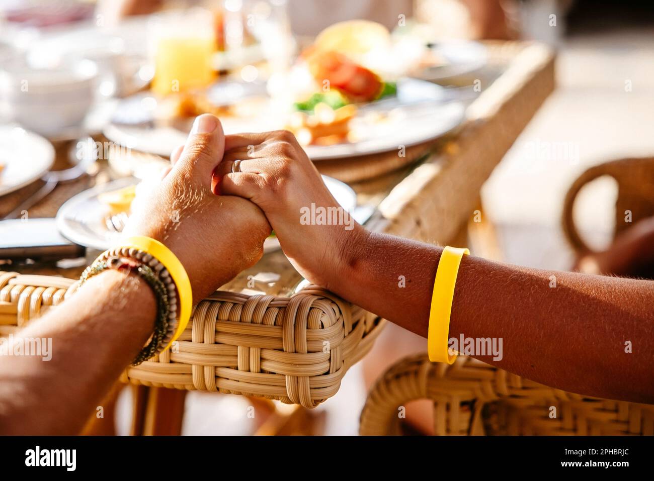 Zugeschnittenes Bild eines heterosexuellen Paares, das am Tisch im Resort Händchen hält Stockfoto