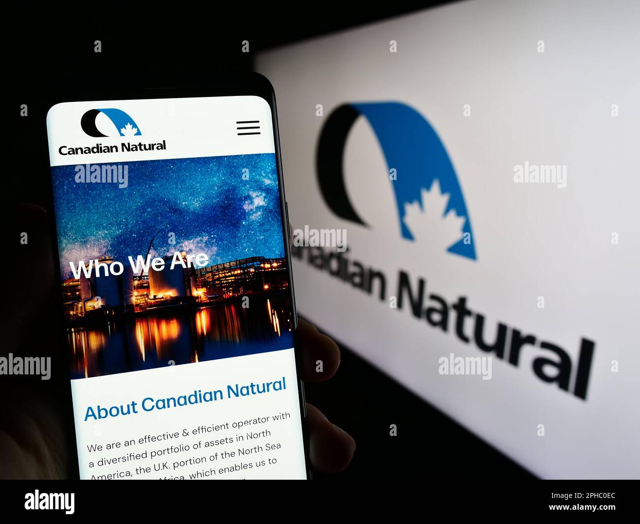Person mit Mobiltelefon und Website des Unternehmens Canadian Natural Resources Limited auf dem Bildschirm mit Logo. Konzentrieren Sie sich auf die Mitte des Telefondisplays. Stockfoto