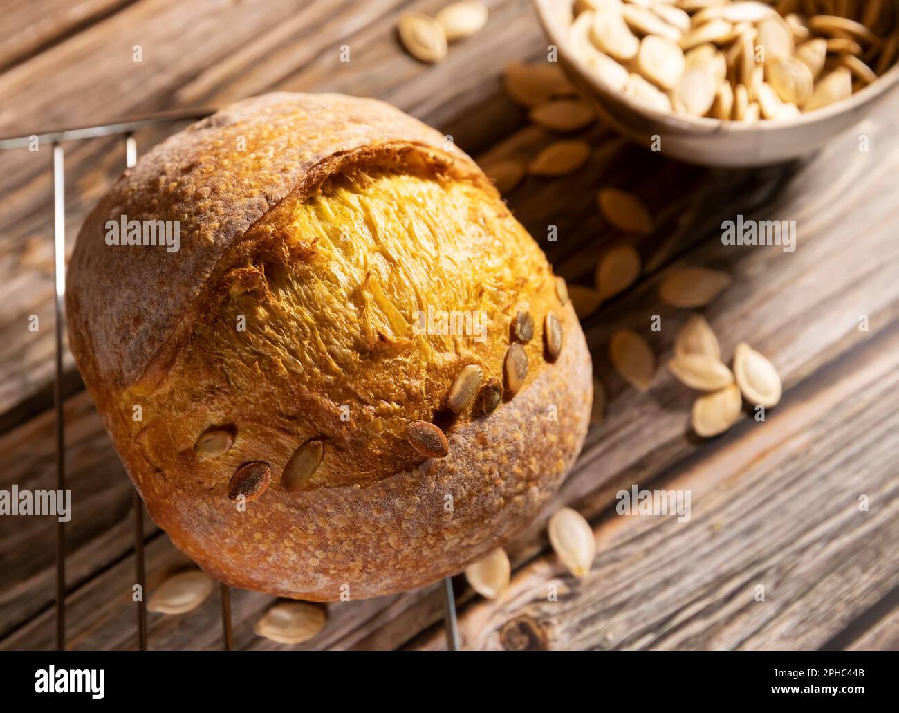 Brot; traditionelles Sauerteigbrot; runde Form mit Kürbiskernen auf rustikalem Holzhintergrund. Das Konzept der traditionellen Backen ohne Hefe Stockfoto