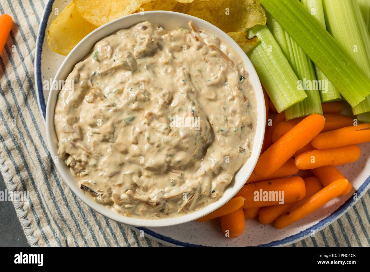 Hausgemachtes, gesundes, karmelisiertes Zwiebeldip mit Chips und Sellerie Stockfoto