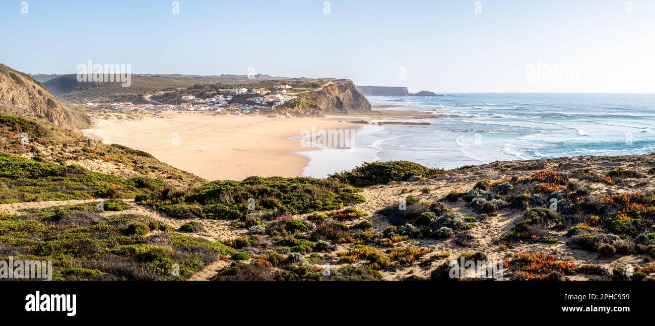 Atemberaubender Panoramablick über den Strand Praia de Monte Clérigo, mit Blick auf die wunderschöne Küste, das blaue Wasser und das bezaubernde Dorf zwischen Klippen. Stockfoto