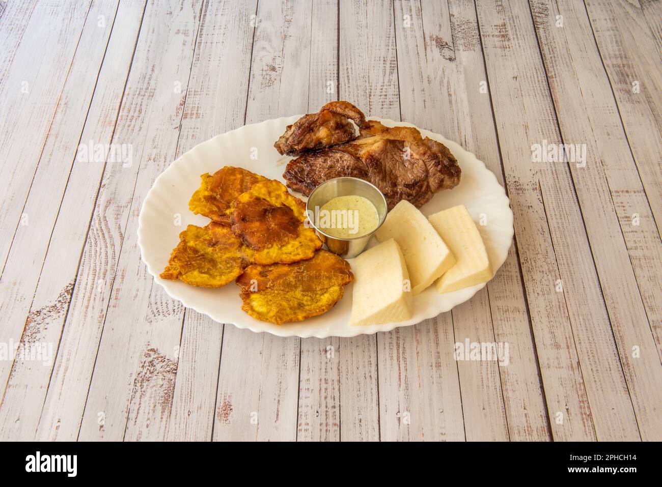 Ein lateinamerikanisches Rezept für Rindersteak mit Handkäse und Patacone mit Sauce Stockfoto