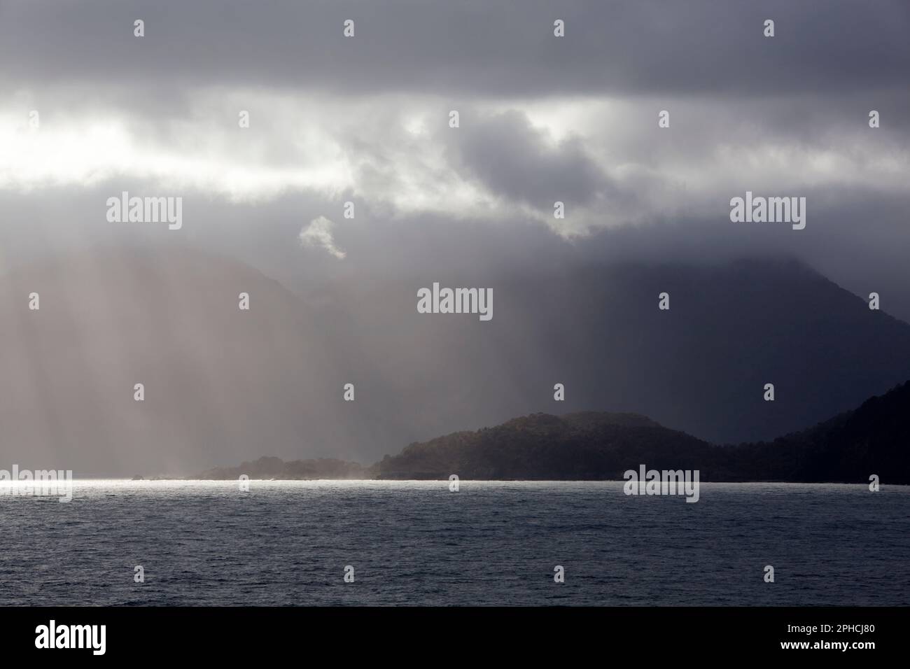 Der Blick am Morgen auf eine bewölkte bergige Küste mit Sonnenlicht im Fiordland-Nationalpark (Neuseeland). Stockfoto