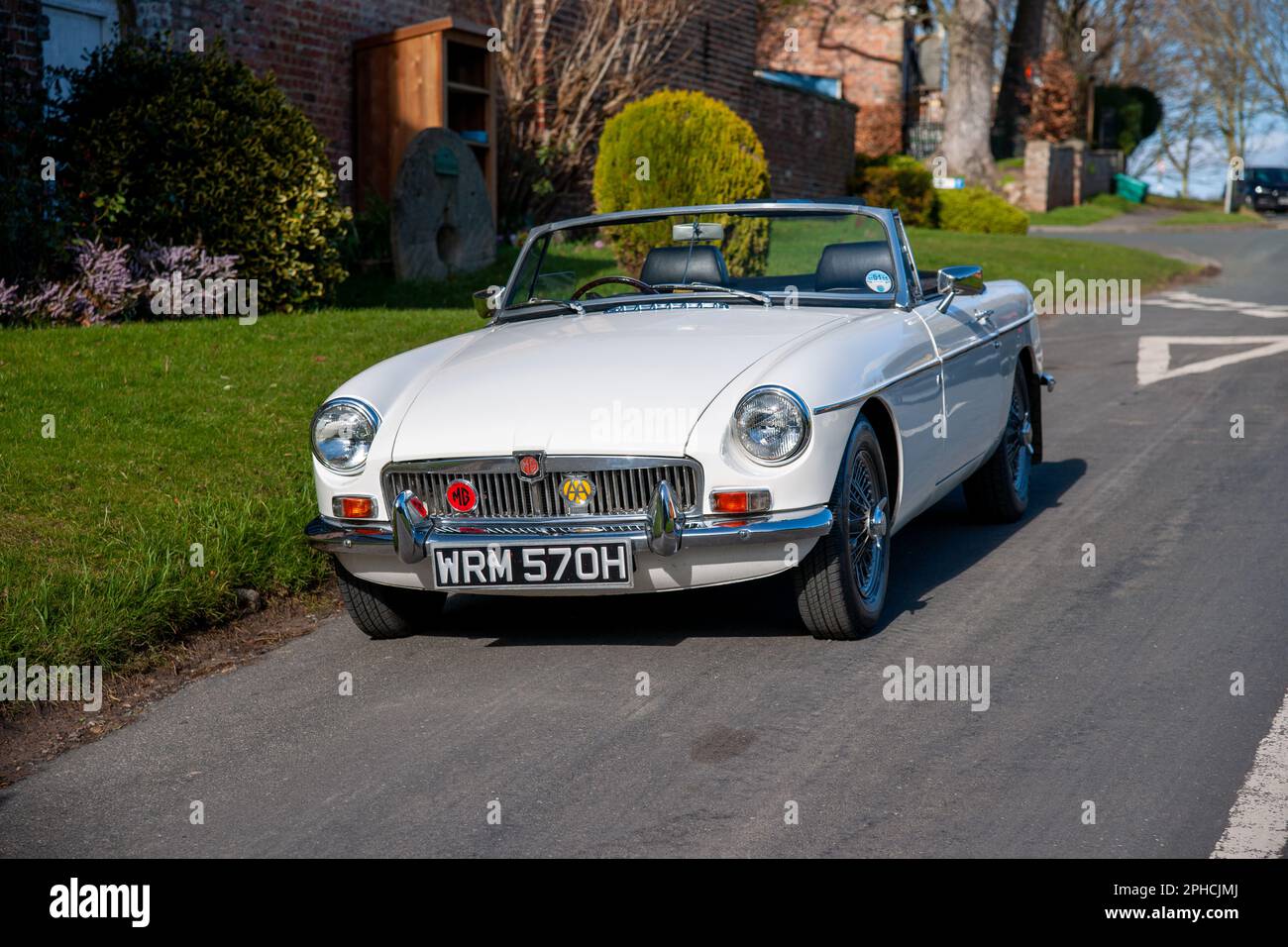 Chrom-Stoßfänger MGB Roadster britischer Klassiker parkt an einem sonnigen Frühlingstag auf einer Landstraße in einem Dorf Stockfoto
