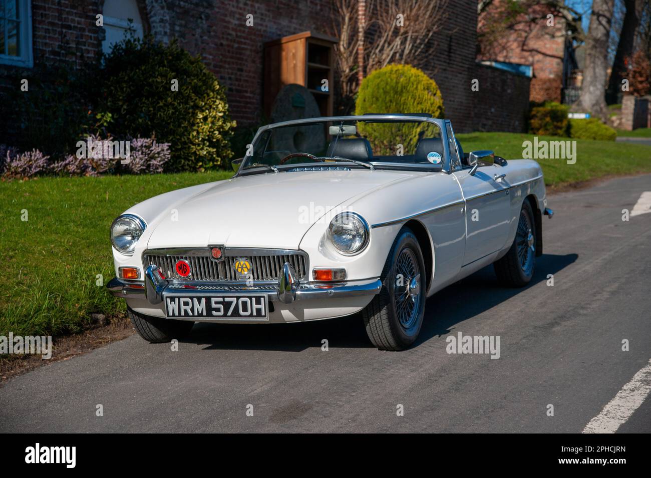 Chrom-Stoßfänger MGB Roadster britischer Klassiker parkt an einem sonnigen Frühlingstag auf einer Landstraße in einem Dorf Stockfoto