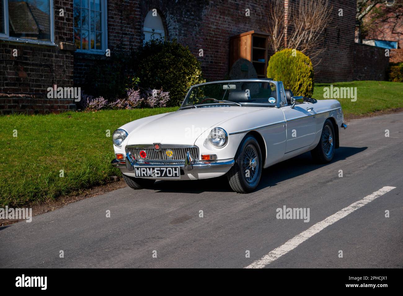 Chrom-Stoßfänger MGB Roadster britischer Klassiker parkt an einem sonnigen Frühlingstag auf einer Landstraße in einem Dorf Stockfoto