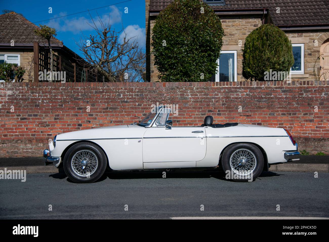 Chrom-Stoßfänger MGB Roadster britischer Klassiker parkt an einem sonnigen Frühlingstag auf einer Landstraße in einem Dorf Stockfoto