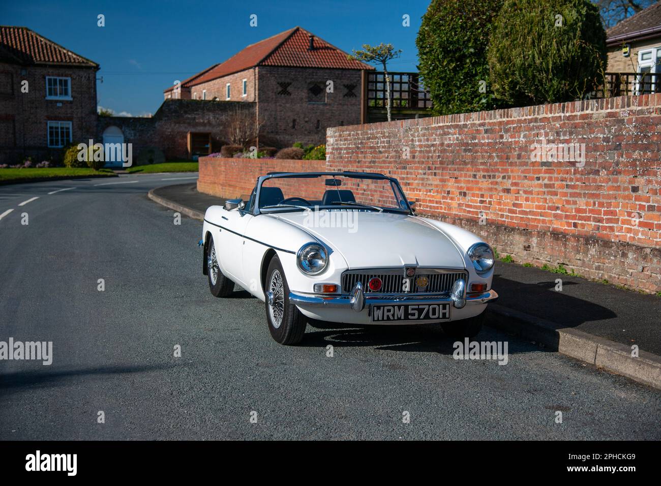 Chrom-Stoßfänger MGB Roadster britischer Klassiker parkt an einem sonnigen Frühlingstag auf einer Landstraße in einem Dorf Stockfoto