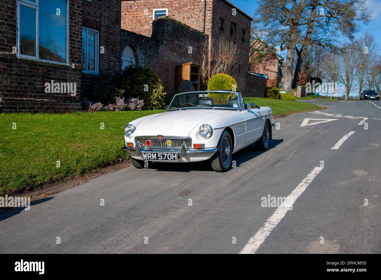 Chrom-Stoßfänger MGB Roadster britischer Klassiker parkt an einem sonnigen Frühlingstag auf einer Landstraße in einem Dorf Stockfoto