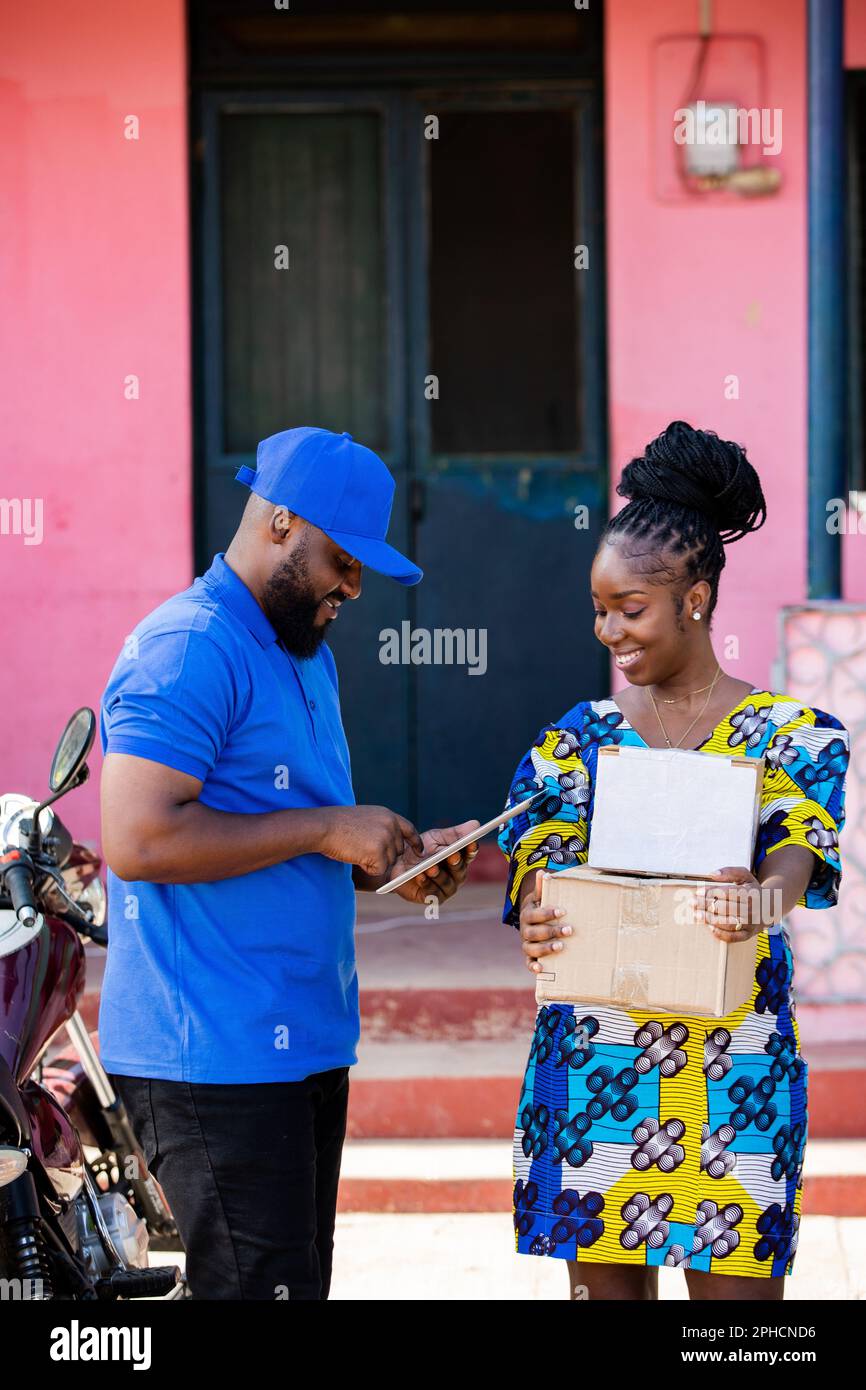 Afrikanischer Kurierfahrer vom örtlichen Postversand liefert Postpakete mit Motorrad an weibliche Kunden zu Hause, Kopierraum. Stockfoto