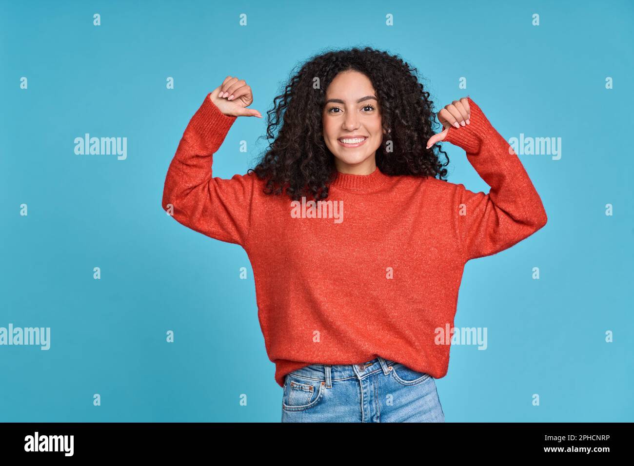 Junge, glückliche latina, die auf sich selbst zeigt, isoliert auf blauem Hintergrund. Stockfoto