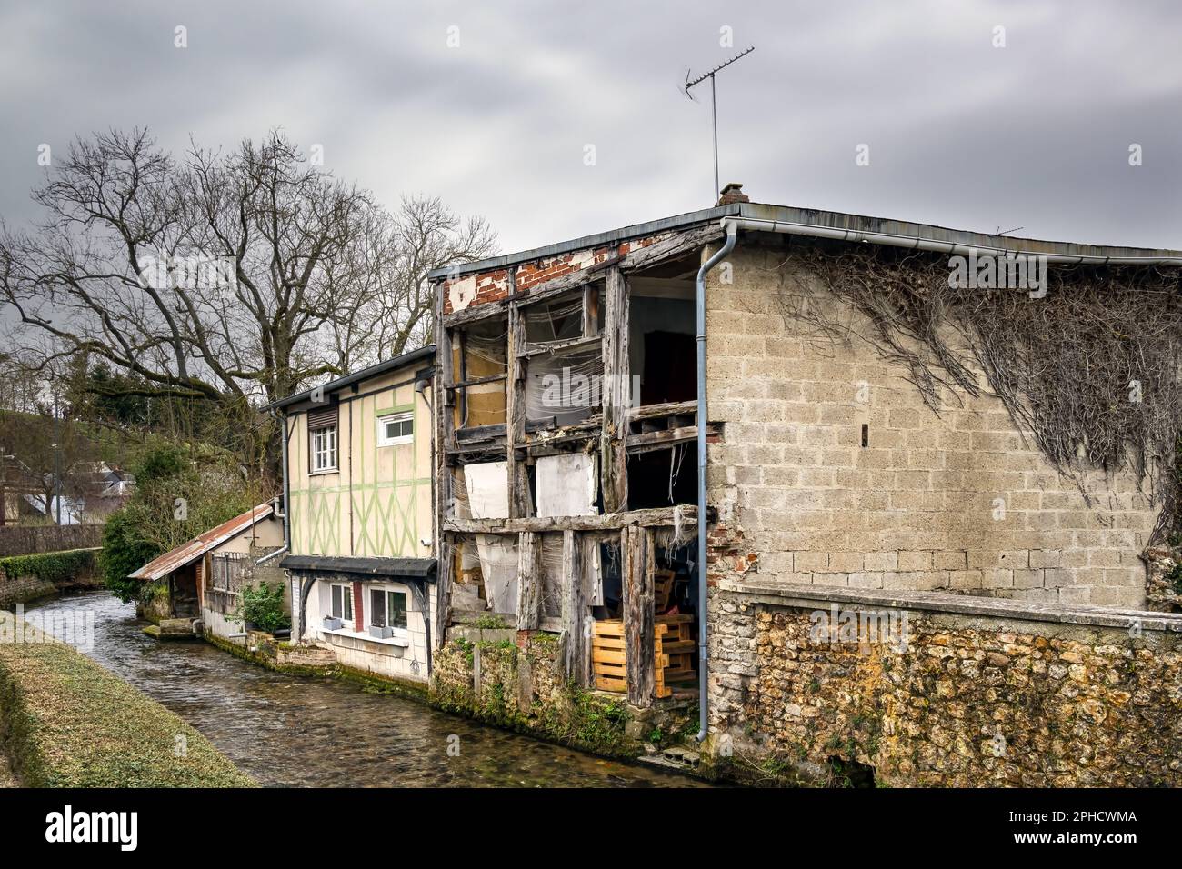 Verfallene Bauarbeiten am Ufer des Flusses Le Cosnier im Winter in Bernay, Eure, Normandie, Frankreich Stockfoto