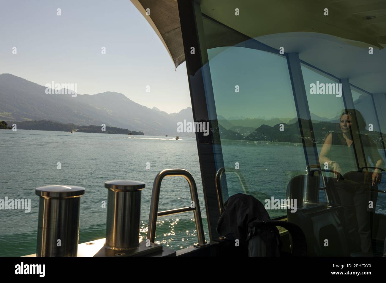 Frau im Fenster auf einem Passagierschiff an einem sonnigen Sommertag auf dem Vierwaldstättersee mit Berg in der Schweiz. Stockfoto