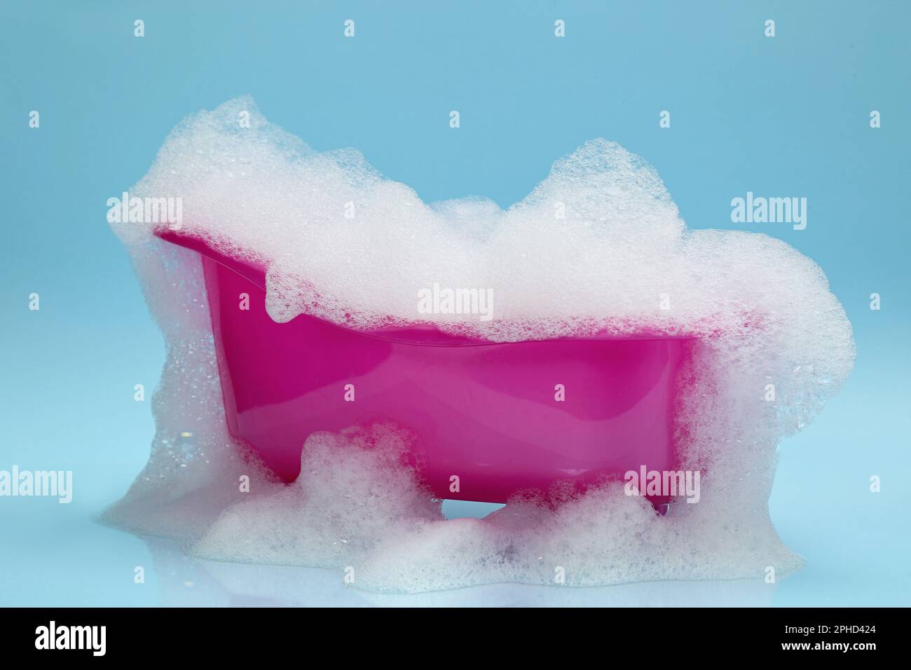 Spielzeugbadewanne mit Schaumstoff auf hellblauem Hintergrund Stockfoto