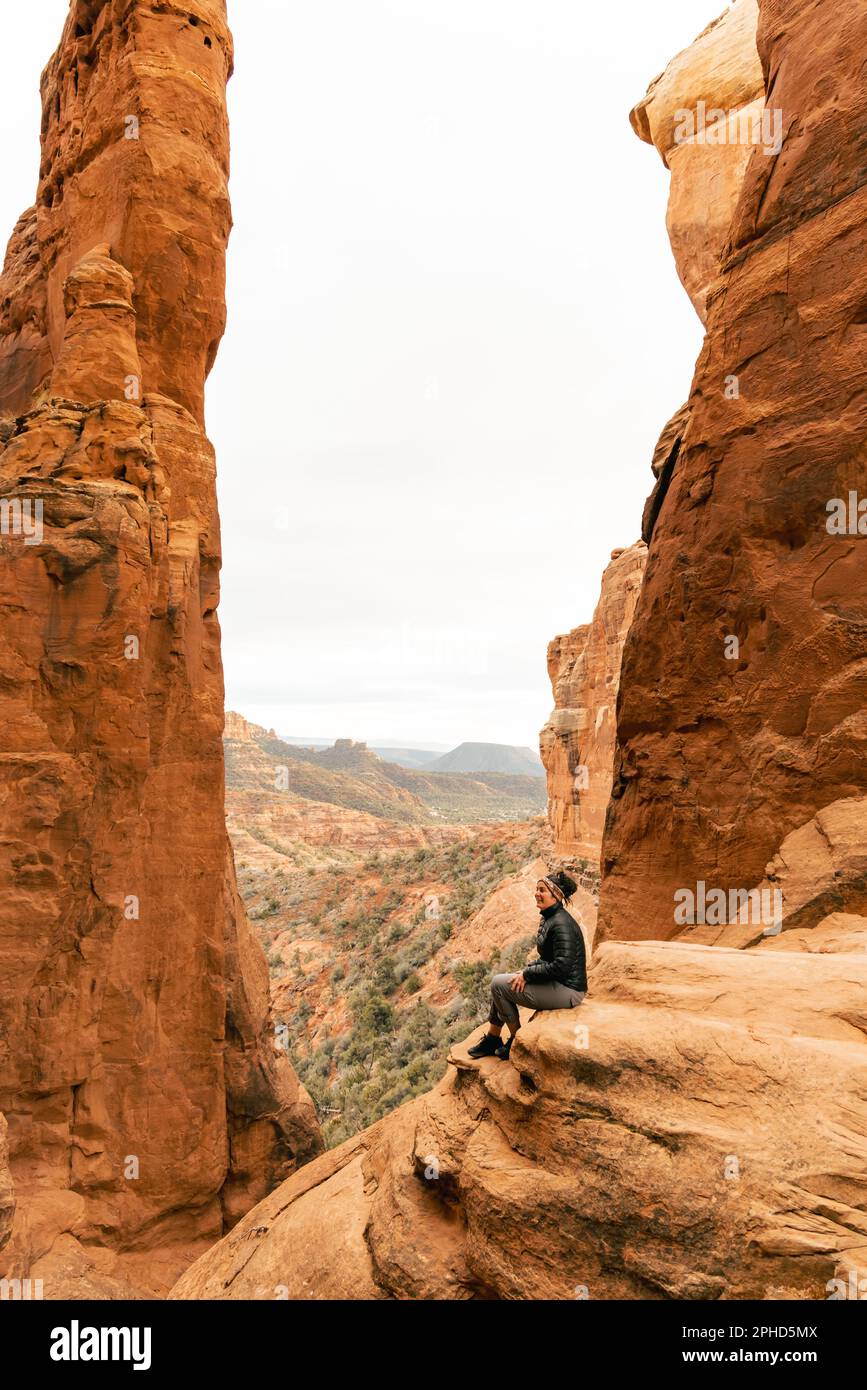 Eine Frau sieht lachend am Aussichtspunkt des Cathedral Rock Gipfels auf. Stockfoto