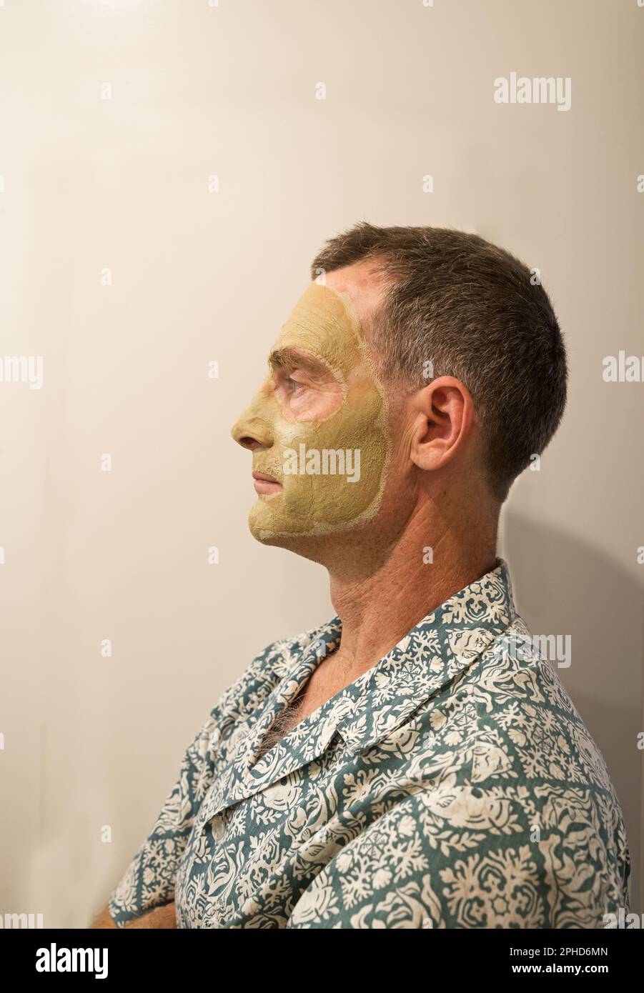 Seitenansicht eines Mannes mittleren Alters mit einer grünlichen Tongesichtsmaske Stockfoto