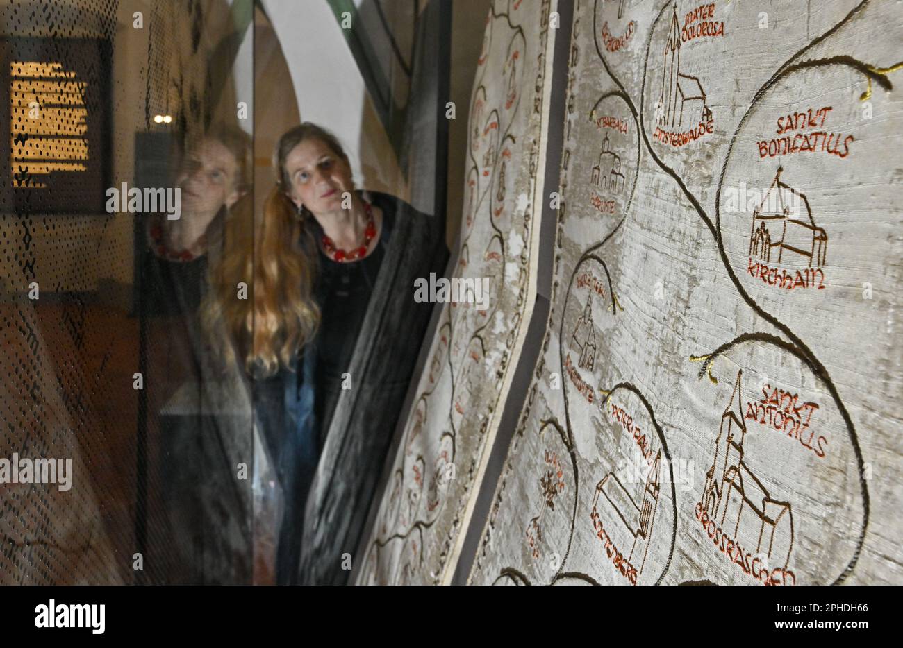 PRODUKTION - 24. März 2023, Brandenburg, Neuzelle: Dorothee Schmidt-Breitung, Restauratorin, blickt auf Fallschirmseide mit dem Wallfahrtslied Neuzell in der Klosterausstellung Neuzelle. Der 1268 gegründete Klosterkomplex Neuzelle wird seit Jahrzehnten renoviert und für Besucher entwickelt. Bisher sind rund 60 Millionen Euro in das Denkmal geflossen, das als Barockwunder Brandenburgs beschrieben wird. Ab dem 1. April können sich die Gäste zurechtfinden und noch besser Informationen erhalten. (Zu dpa 'alles neue im alten Kloster - Eine Tour durch das permanente e Stockfoto